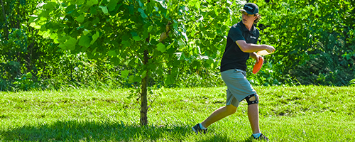 An older child throwing a disc from behind a tree